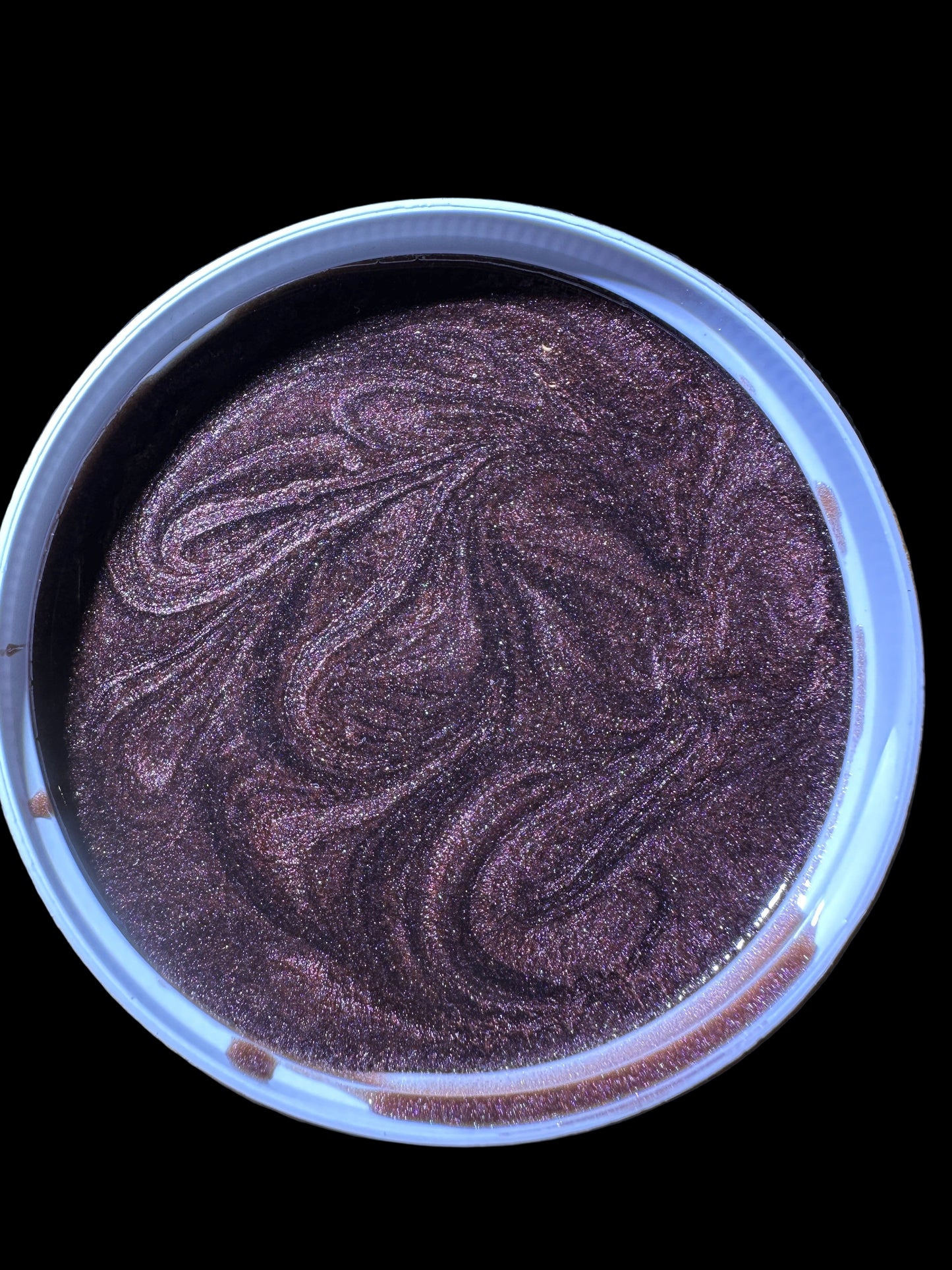 Container with purple and white marbled substance on a wooden surface